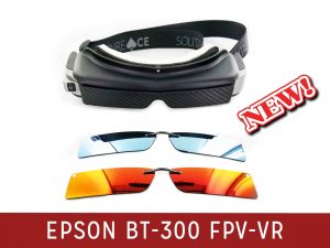 A black and silver pair of smart glasses with a thick black head strap. A pair of silver polarized clip-on lenses. A pair of orange-tinted polarized clip-on lenses.