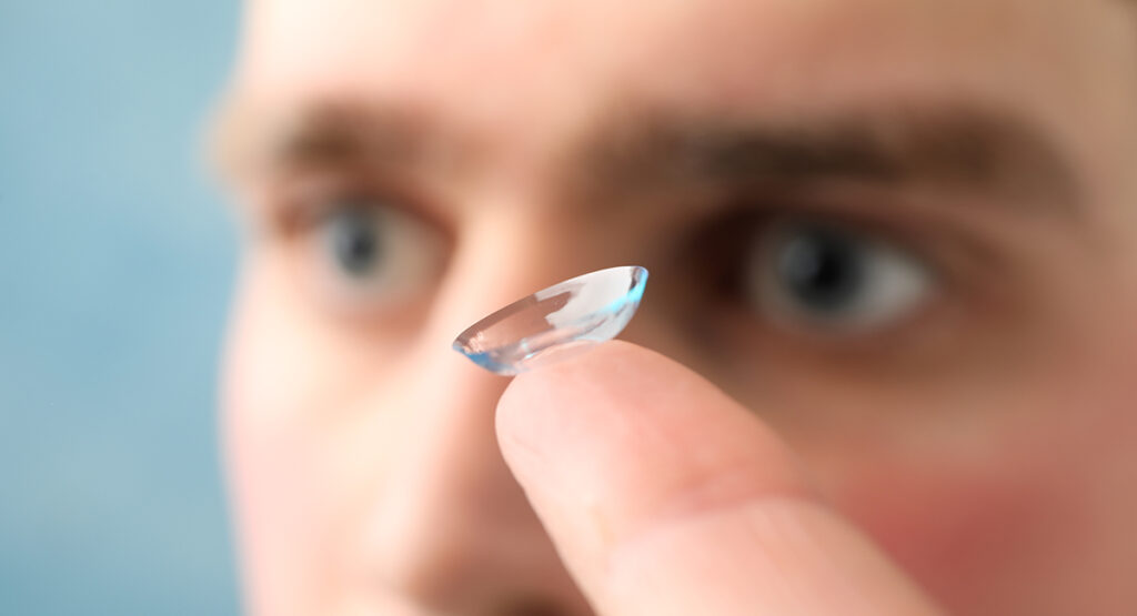 image of a man holding a contact lense
